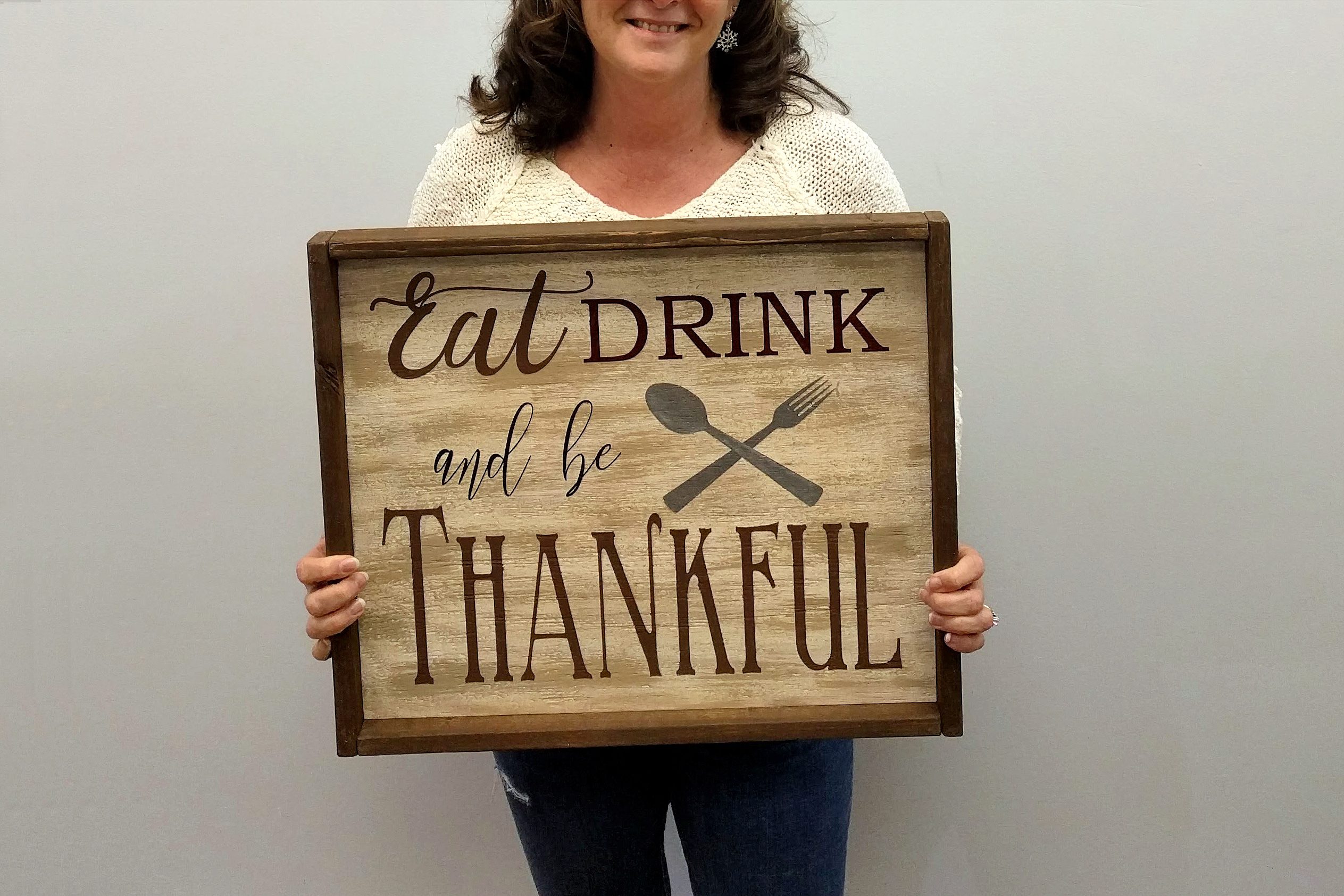woman holding wood sign that says eat drink and be thankful